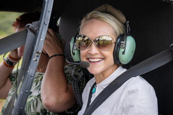 Camille Rowe on a helicopter safari in Africa, wearing a headset and looking out over the wilderness.