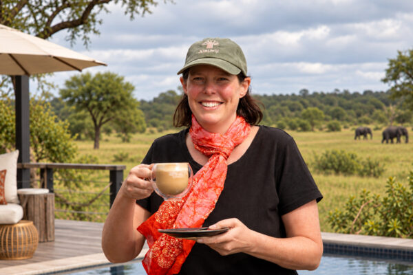 Lise Kargaard enjoying a coffee at Ximuwu Lodge with elephants in the background